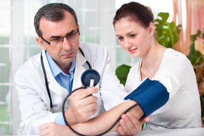 Arzt misst den Blutdruck und Puls bei Patientin